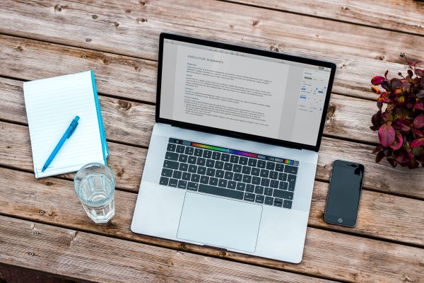 A laptop, notebook, phone and glass of water