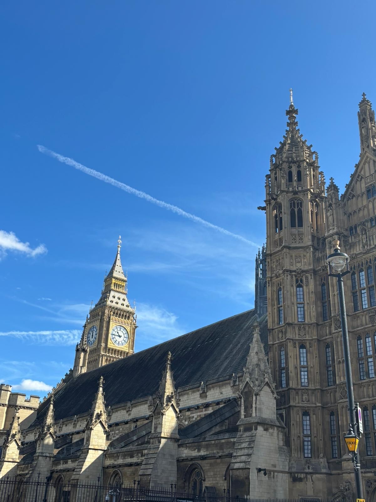 A picture at the Houses of Parliament with a blue sky and the top of Big Ben can be seen in the back