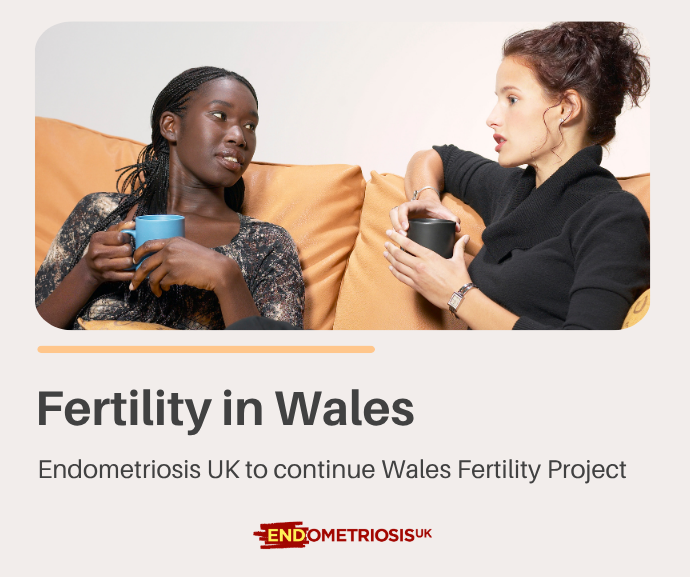 Two women sit together on an orange sofa holding mugs and talking, above text reading 'Fertility in Wales: Endometriosis UK to continue Wales Fertility Project,' with the Endometriosis UK logo below.