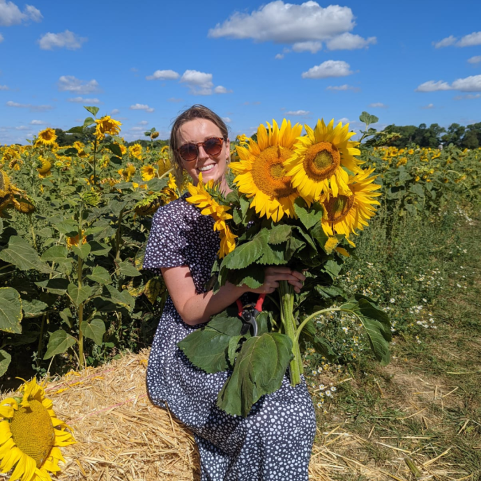 Gina smiling holding sunflowers