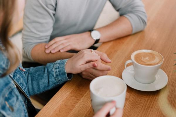 Friends holding hands over coffee