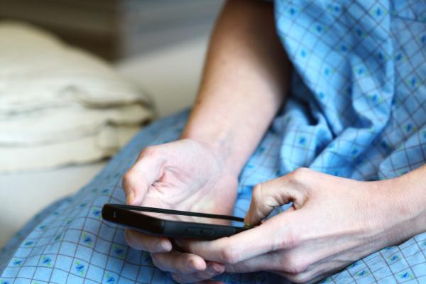 Woman in hospital gown holding smartphone