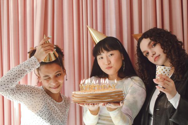 Three people with party hats and a cake