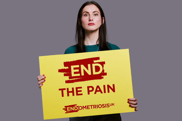Woman holding a placard that says "End The Pain" 