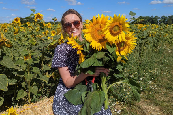 Gina smiling holding sunflowers