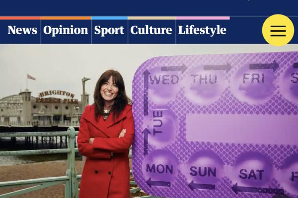 Screenshot from the Guardian - a photo of Davina McCall in a red coat standing next to a giant purple blister pack of contraceptive pills