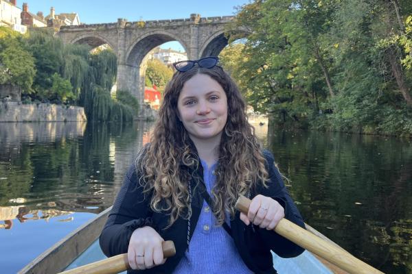 A photograph of Maeve, sitting in a rowing boat and smiling.