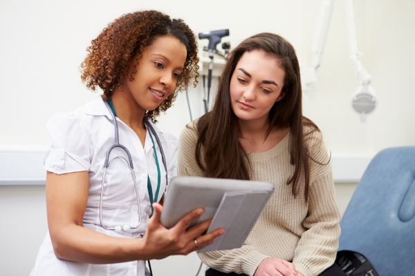 A photo of a young woman and a doctor looking over notes