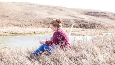 A woman sits in a field