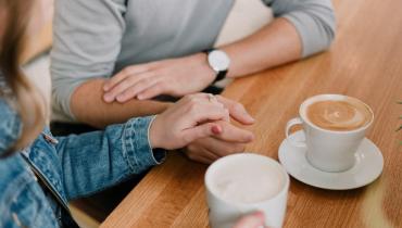 Friends holding hands over coffee