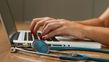 A doctor typing on a laptop