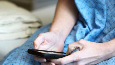 Woman in hospital gown holding smartphone