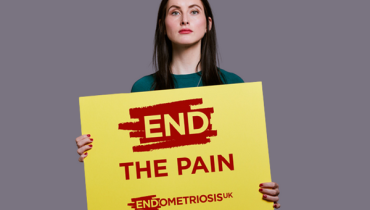 Woman holding a placard that says "End The Pain" 